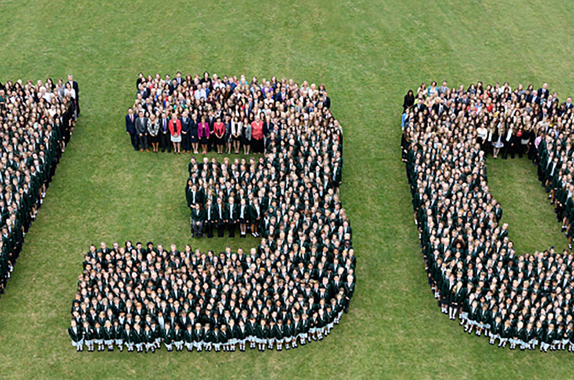 Aerial group photograph with pupils standing in shape of the numbers "130"